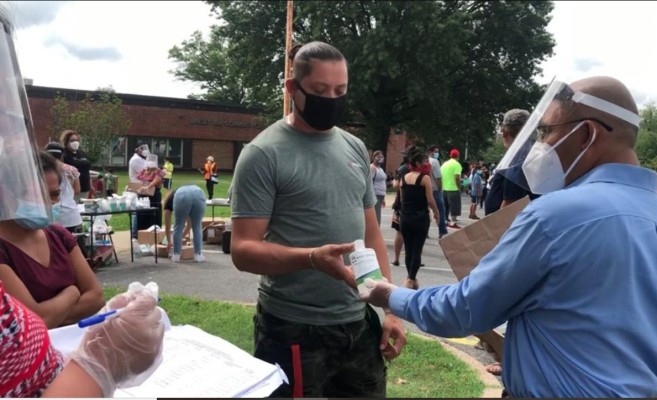 At a distribution of free PPE to indigenous people of the DC metro area, a Masks For America volunteer gives Nurses Station Hand Sanitizer to a community member. Photograph: Sebi Medina-Tayac